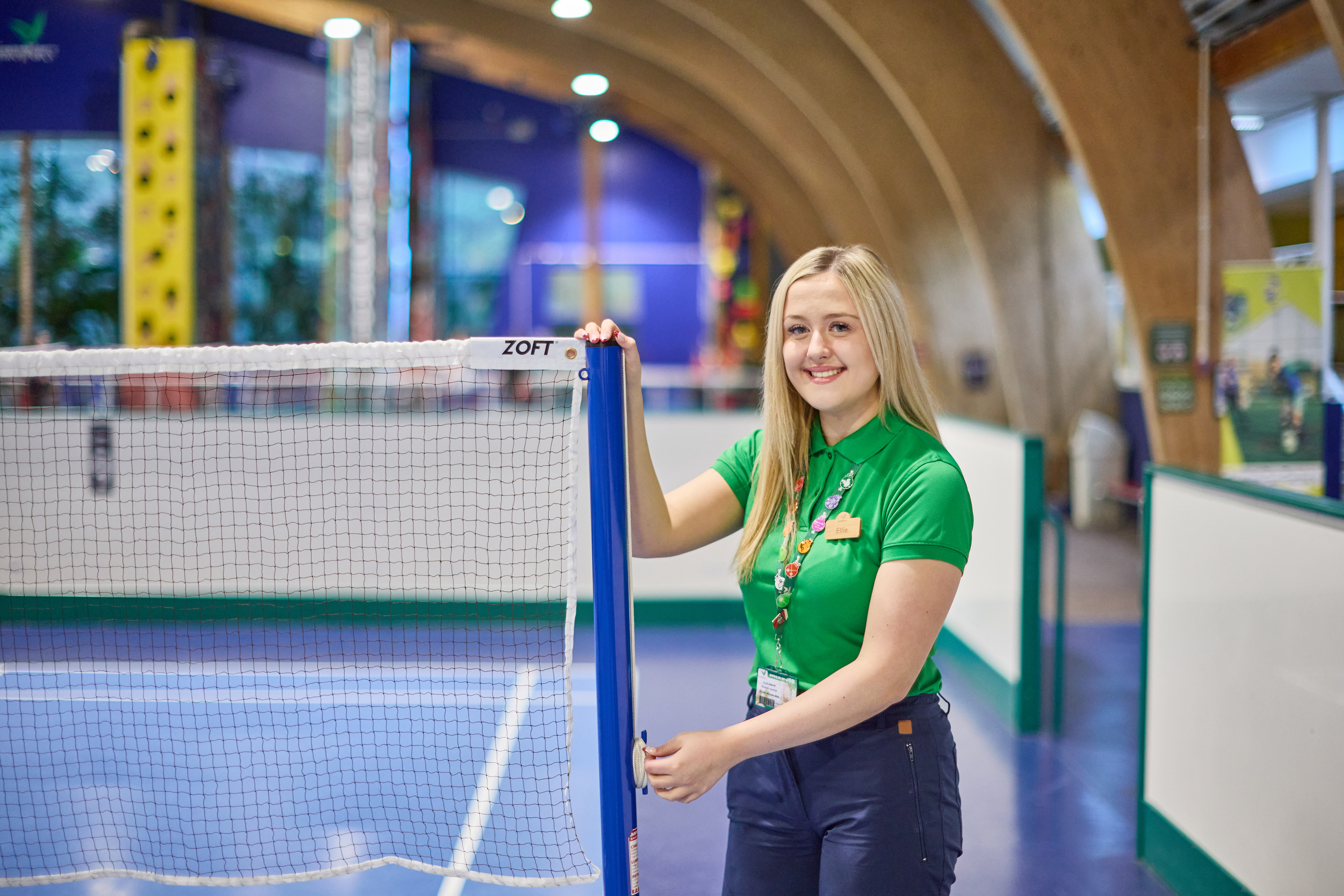 Woman in green shirt by a badminton net.