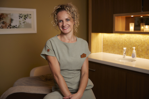Woman in spa uniform smiling at the camera.