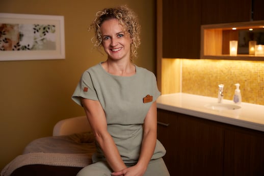 Woman in spa uniform smiling at the camera.
