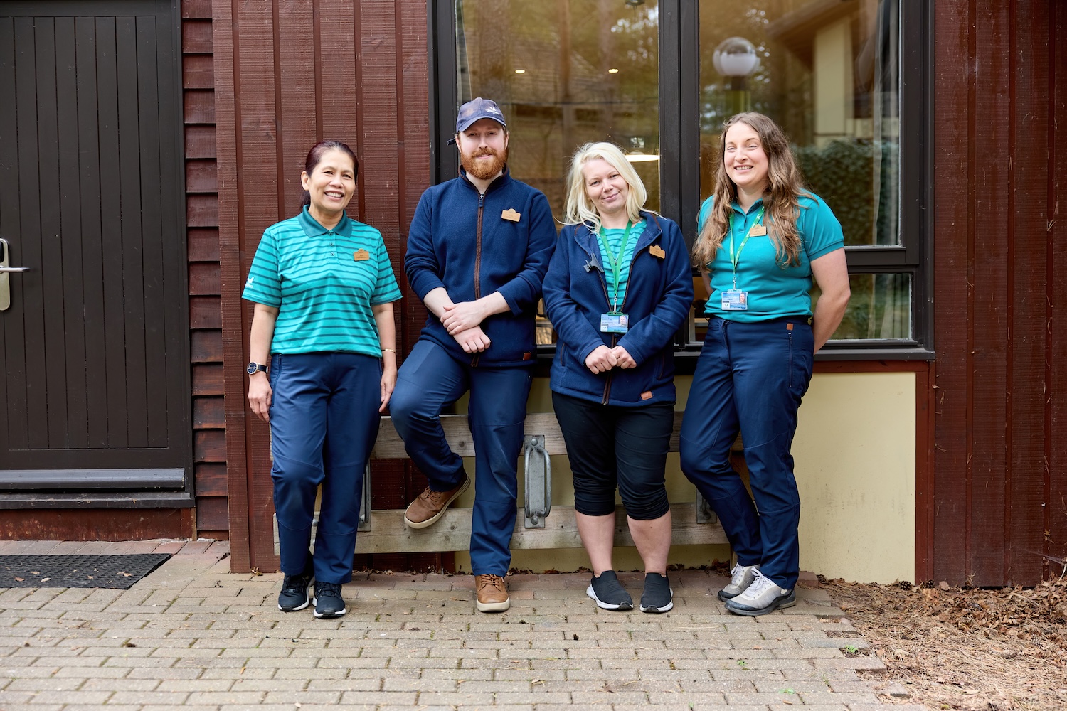 Four staff members in uniform posing outside a building.