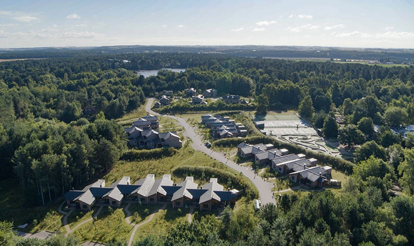 Lodges nestled in a forest, with a tennis court and mini-golf course.