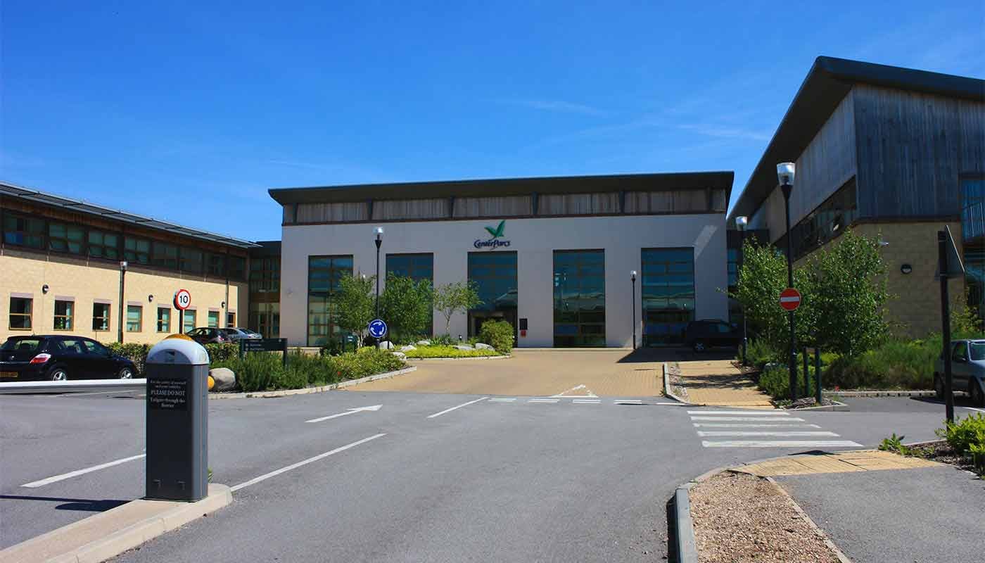 Exterior view of the Center Parcs head office building with parking and road signs.