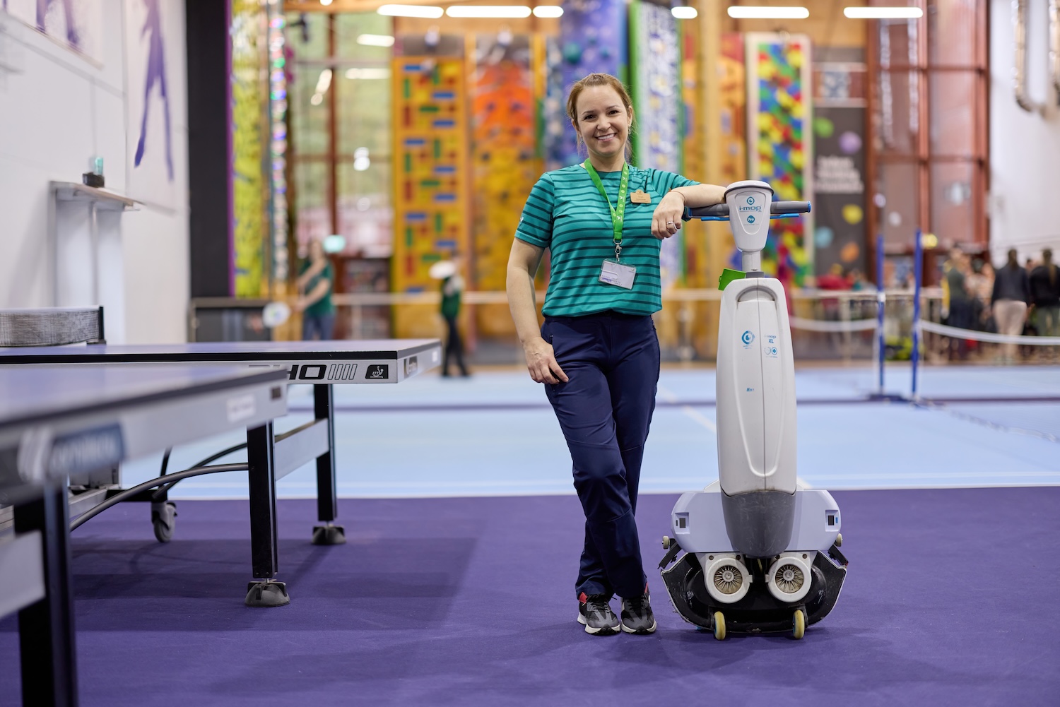 Woman with cleaning robot in a sports facility.