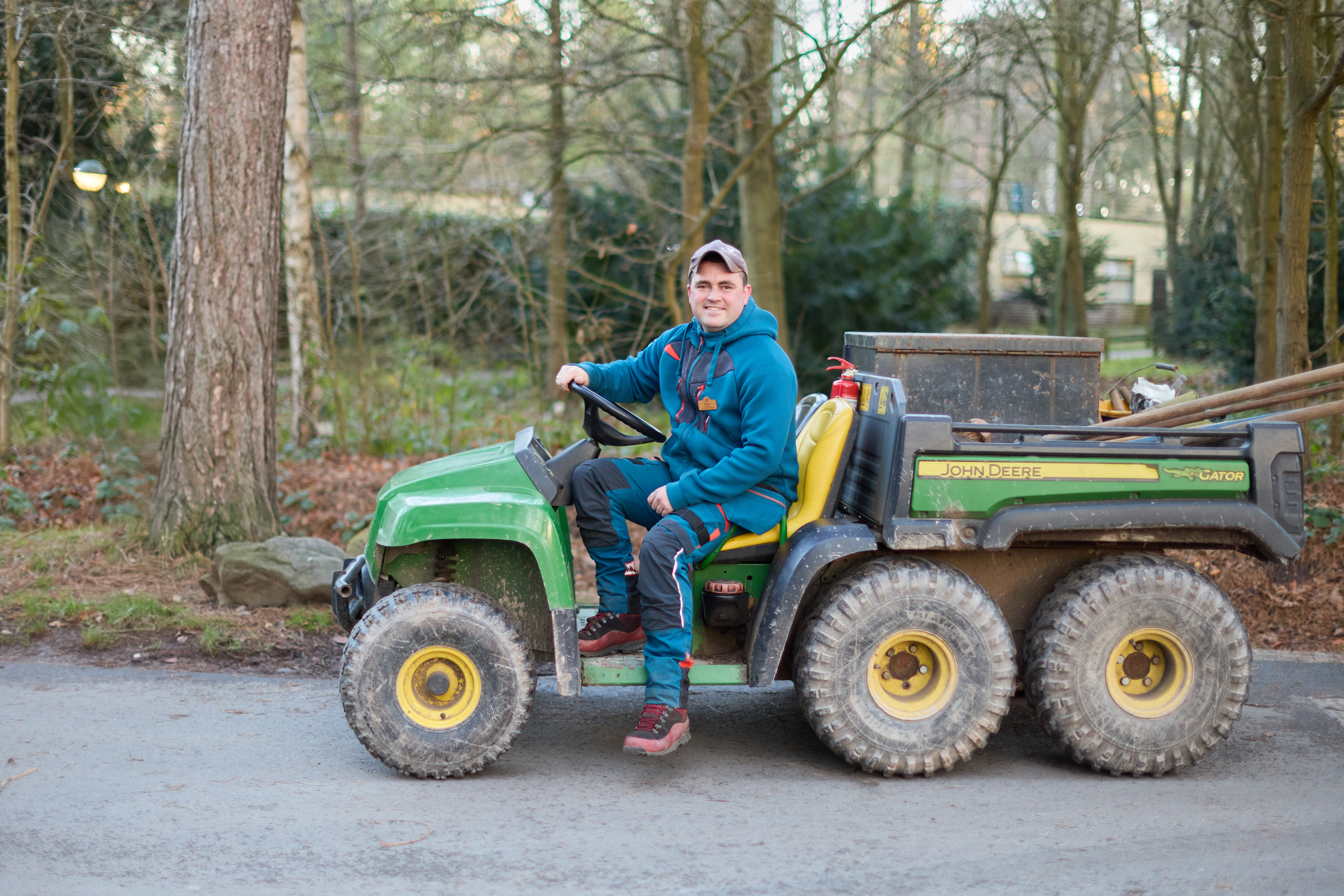 Man in work clothes on a John Deere Gator utility vehicle.