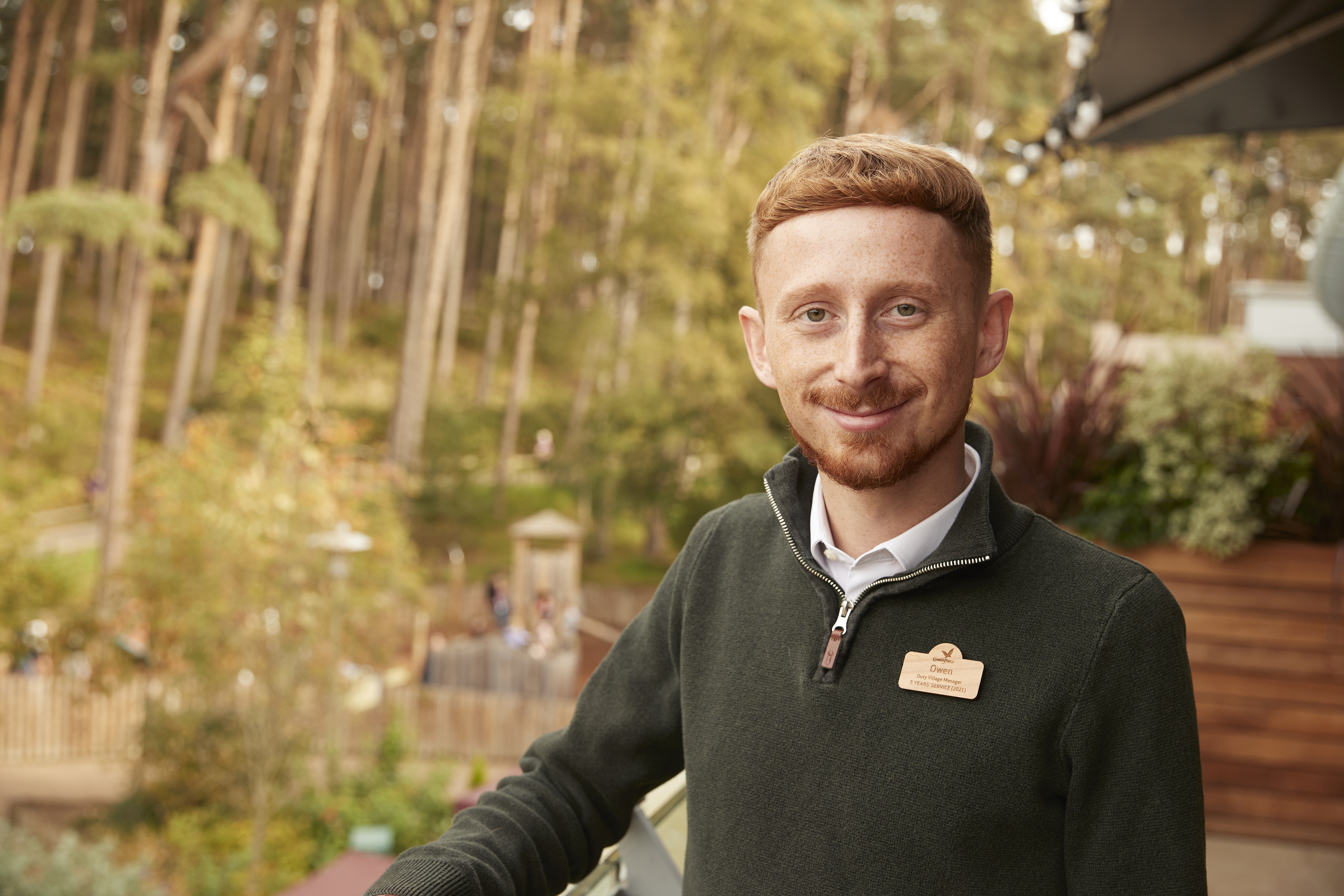 Portrait of a man with red hair, wearing a green sweater.