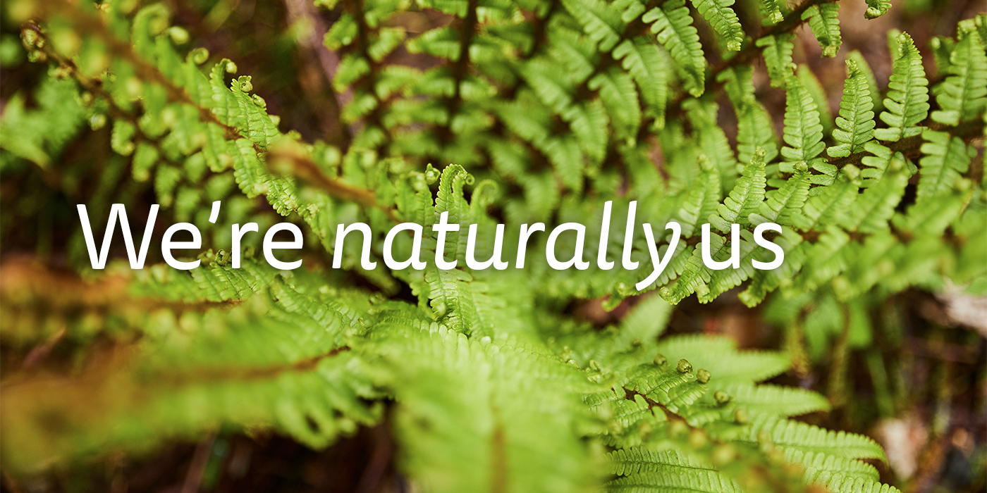 Ferns with the words "We're naturally us".
