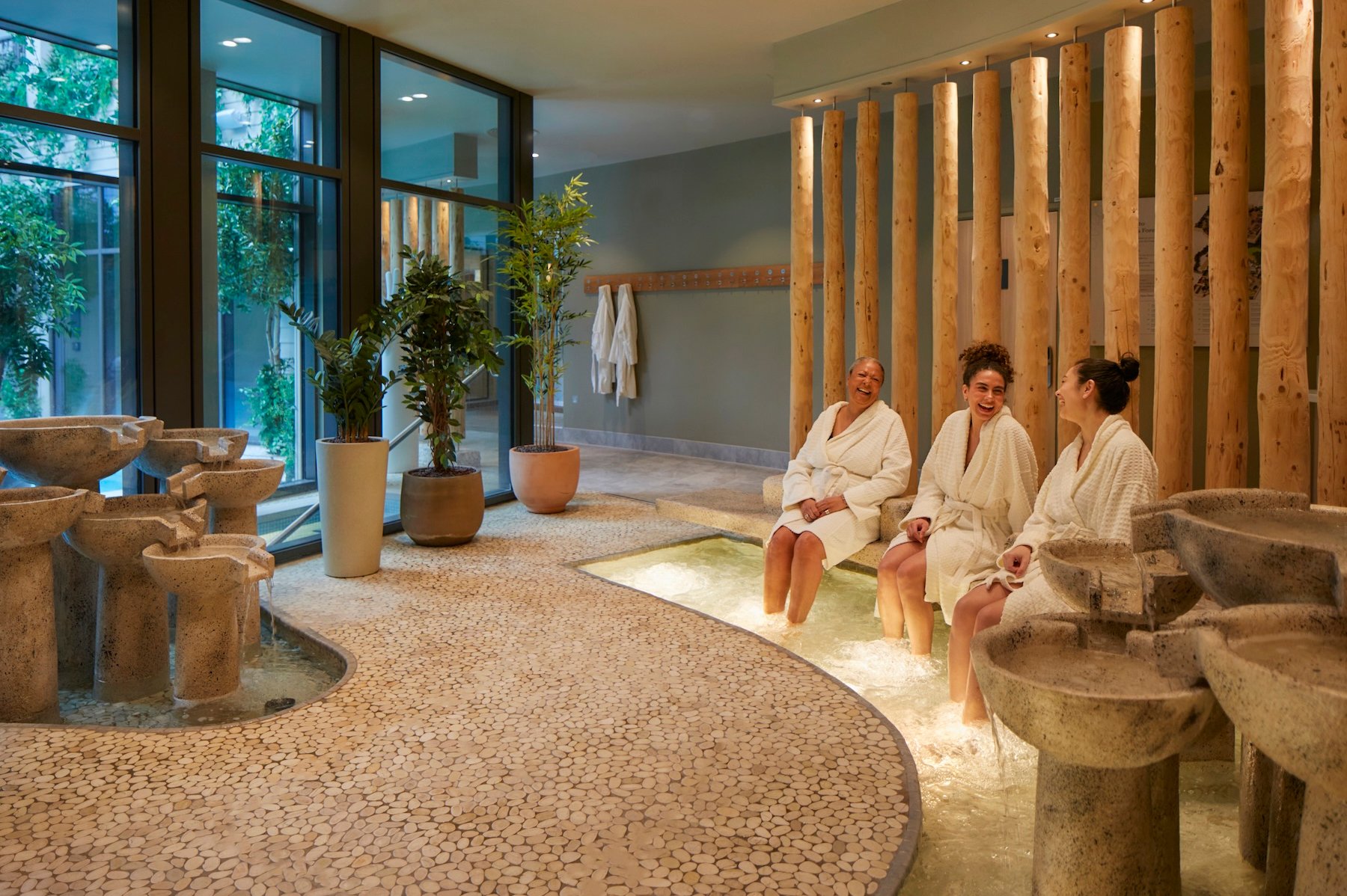 Women in white robes relaxing in a spa with water features.